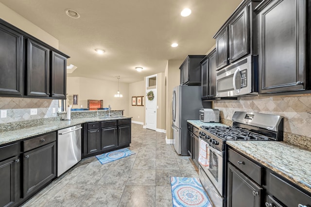 kitchen featuring light stone counters, appliances with stainless steel finishes, tasteful backsplash, and light tile floors