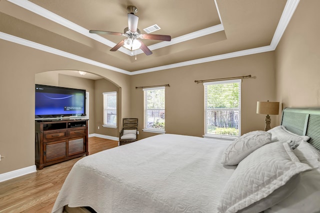 bedroom featuring a tray ceiling, ceiling fan, light hardwood / wood-style floors, and ornamental molding