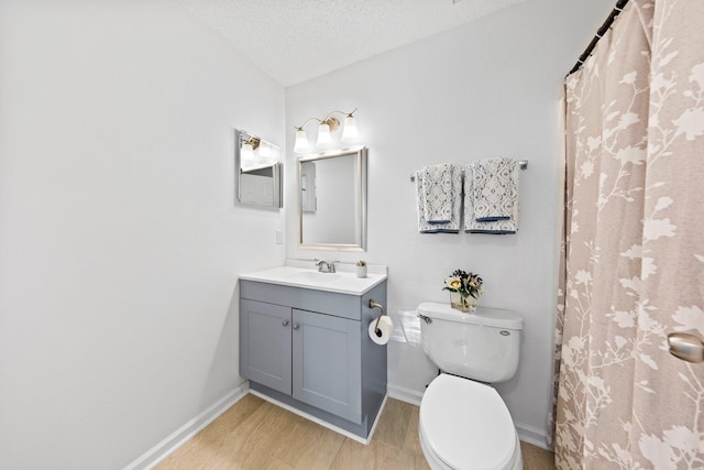 bathroom featuring wood-type flooring, vanity, toilet, and a textured ceiling