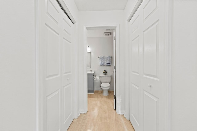 hallway with light wood-type flooring and a textured ceiling