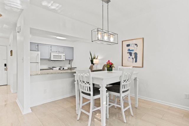 dining space featuring sink and a notable chandelier