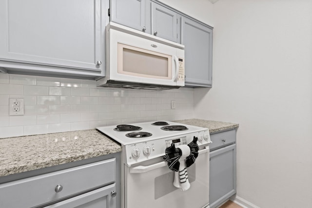 kitchen featuring gray cabinets, white appliances, tasteful backsplash, and light stone countertops