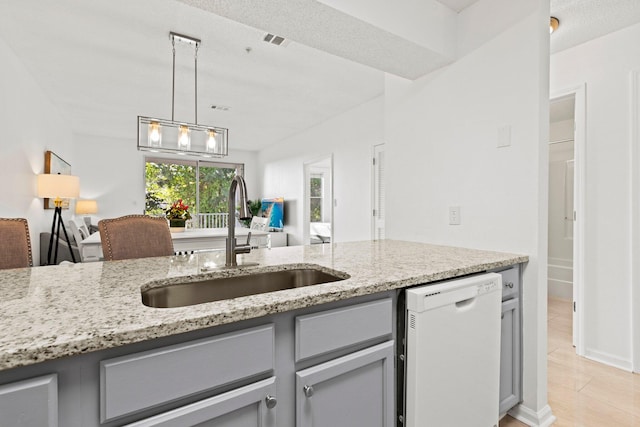 kitchen featuring sink, light stone countertops, white dishwasher, and gray cabinetry