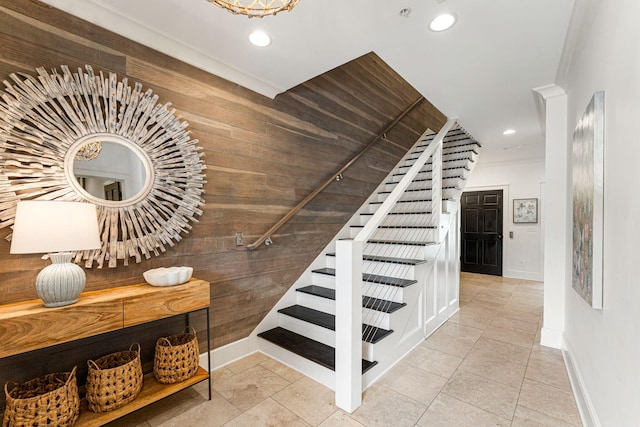 staircase with crown molding, light tile floors, and wooden walls