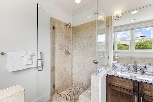 bathroom featuring a shower with shower door, crown molding, and vanity