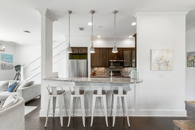 kitchen with tasteful backsplash, appliances with stainless steel finishes, dark wood-type flooring, and a kitchen bar