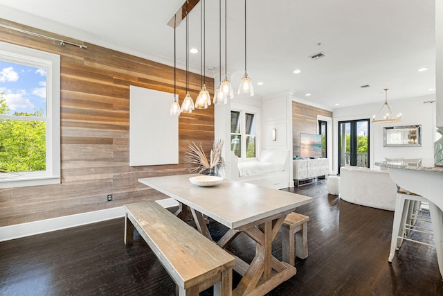 dining area featuring dark hardwood / wood-style floors, wood walls, and a chandelier