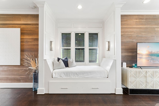 bedroom with ornamental molding, wooden walls, and dark hardwood / wood-style floors