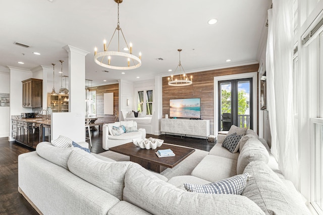 living room with ornamental molding, wood walls, dark wood-type flooring, and sink