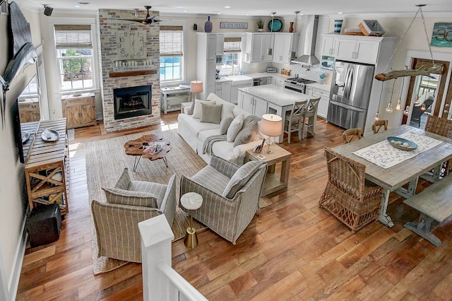 living room with brick wall, light hardwood / wood-style flooring, ceiling fan, and a fireplace