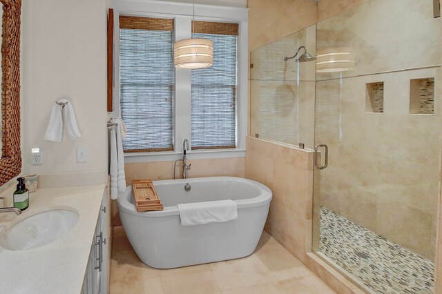 bathroom with tile walls, shower with separate bathtub, tile floors, and vanity