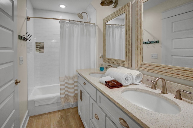 bathroom with hardwood / wood-style flooring, shower / bath combination with curtain, and double vanity