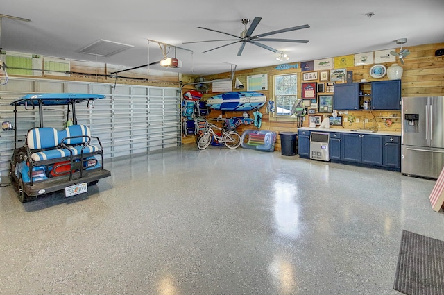 garage featuring ceiling fan, stainless steel refrigerator with ice dispenser, and a garage door opener