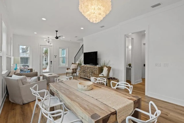 dining room with ceiling fan with notable chandelier and light hardwood / wood-style flooring