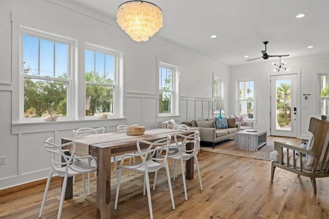 dining room with ceiling fan with notable chandelier and light hardwood / wood-style floors