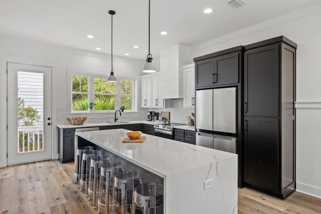 kitchen with a center island, a healthy amount of sunlight, appliances with stainless steel finishes, and light wood-type flooring