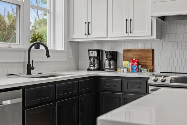 kitchen featuring white cabinets, sink, tasteful backsplash, stainless steel dishwasher, and stove