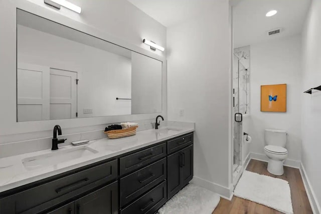 bathroom featuring hardwood / wood-style floors, double vanity, an enclosed shower, and toilet