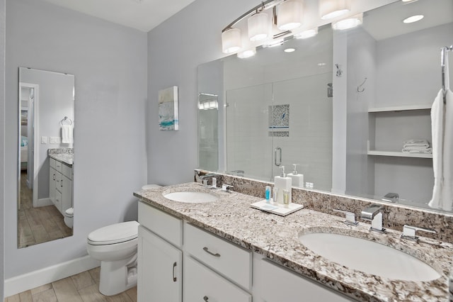 bathroom with dual sinks, an enclosed shower, oversized vanity, and toilet