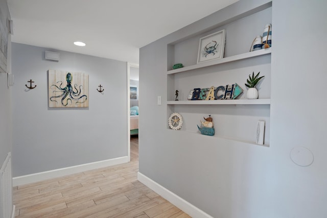 hallway featuring built in features and light hardwood / wood-style floors