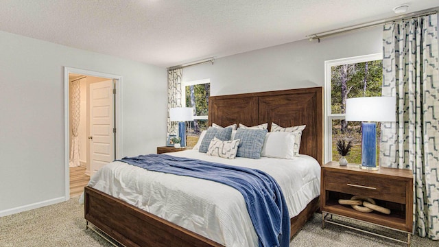 carpeted bedroom featuring a textured ceiling and ensuite bath