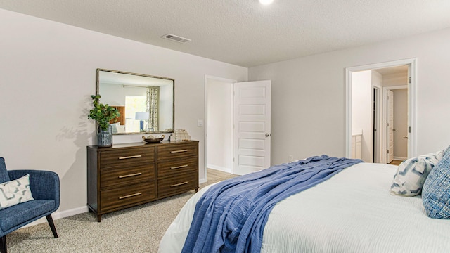 carpeted bedroom featuring ensuite bathroom and a textured ceiling