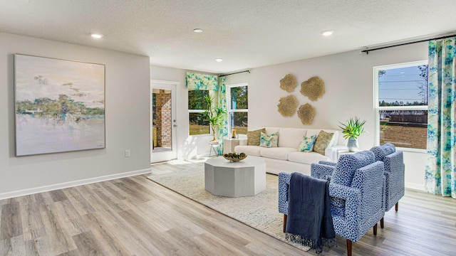 living room with a healthy amount of sunlight, a textured ceiling, and light hardwood / wood-style flooring