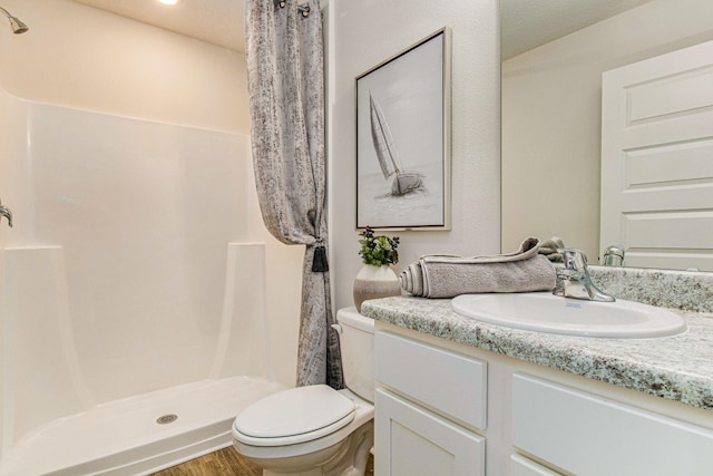 bathroom featuring curtained shower, hardwood / wood-style floors, a textured ceiling, toilet, and vanity