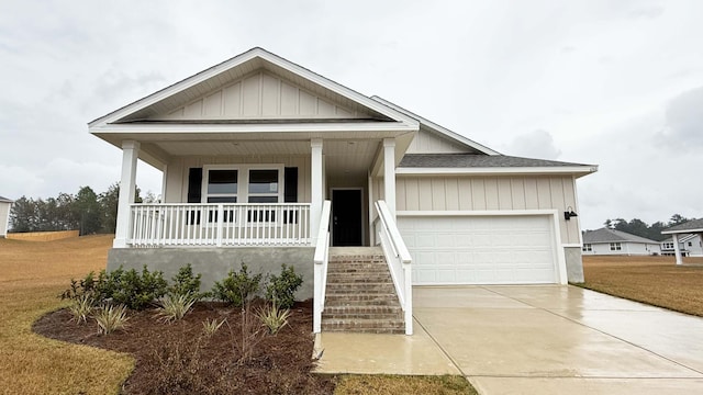 view of front facade with covered porch, a garage, and a front yard