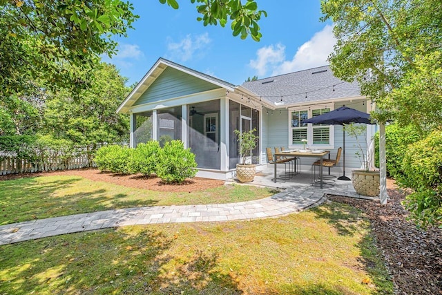 rear view of property featuring a sunroom, a yard, and a patio area