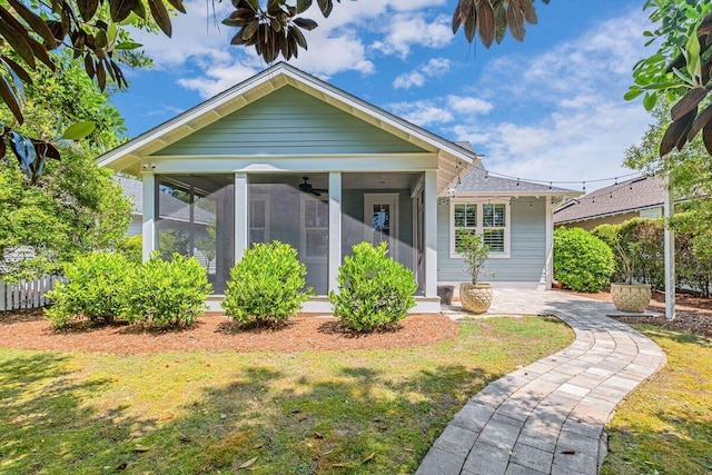 bungalow-style house featuring a sunroom and a front lawn