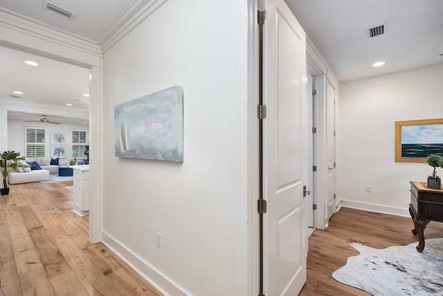 hall with ornamental molding and light hardwood / wood-style floors