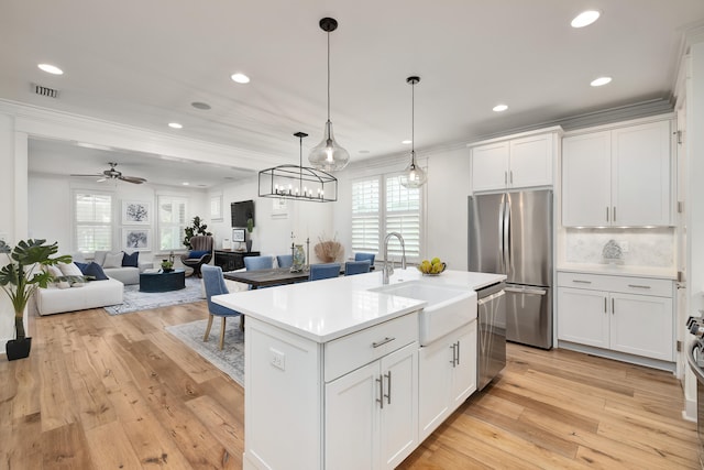 kitchen with stainless steel appliances, white cabinetry, sink, and a center island with sink