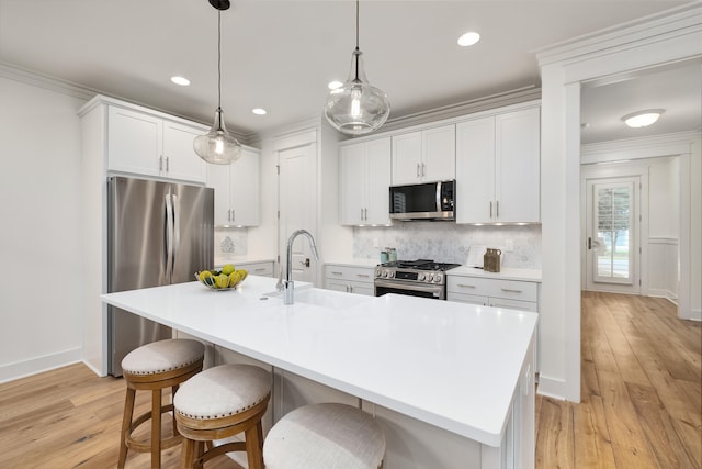 kitchen with stainless steel appliances, sink, a center island with sink, and white cabinets