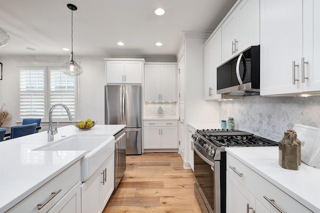 kitchen with white cabinetry, appliances with stainless steel finishes, sink, and light hardwood / wood-style flooring