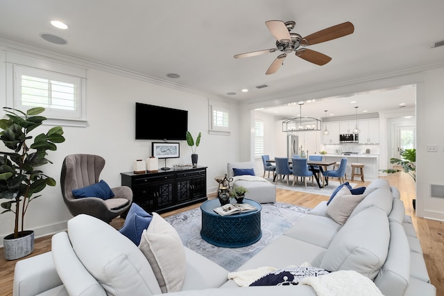 living room featuring crown molding, ceiling fan, and light hardwood / wood-style flooring