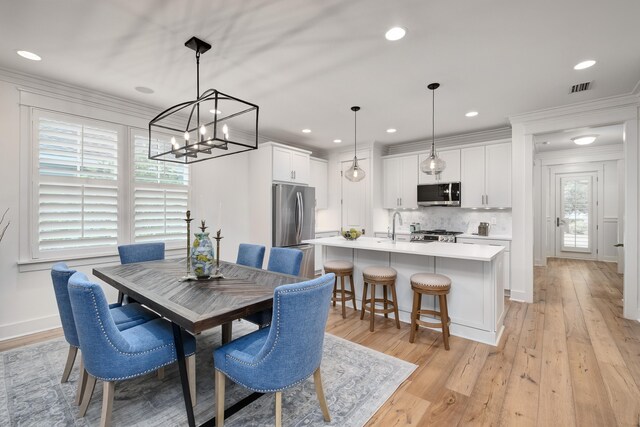 dining space with crown molding, a healthy amount of sunlight, sink, and light wood-type flooring