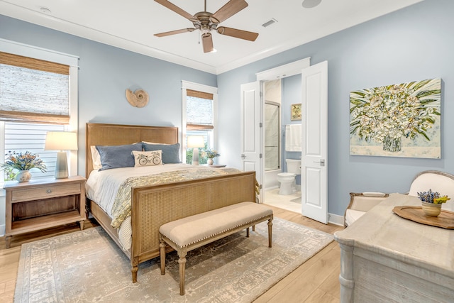 bedroom with light hardwood / wood-style floors, crown molding, ensuite bath, and ceiling fan