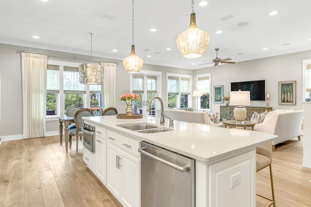 kitchen featuring an island with sink, white cabinetry, sink, light hardwood / wood-style floors, and stainless steel appliances