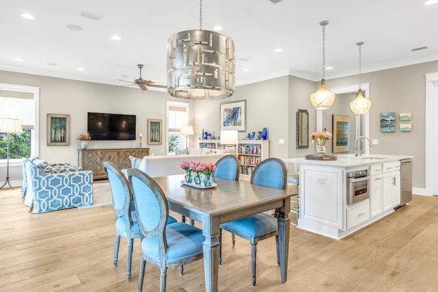 dining area with sink, crown molding, and light wood-type flooring