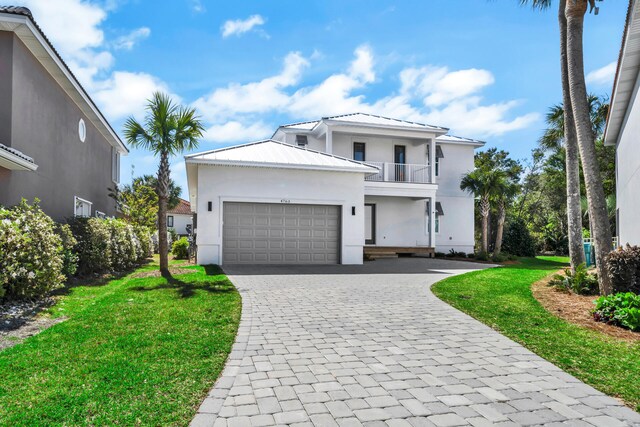 view of front of house featuring a balcony, a front yard, and a garage