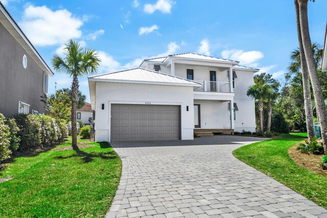 view of front of home with a balcony, a front yard, and a garage