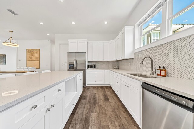 kitchen featuring light stone counters, stainless steel appliances, dark hardwood / wood-style flooring, sink, and tasteful backsplash