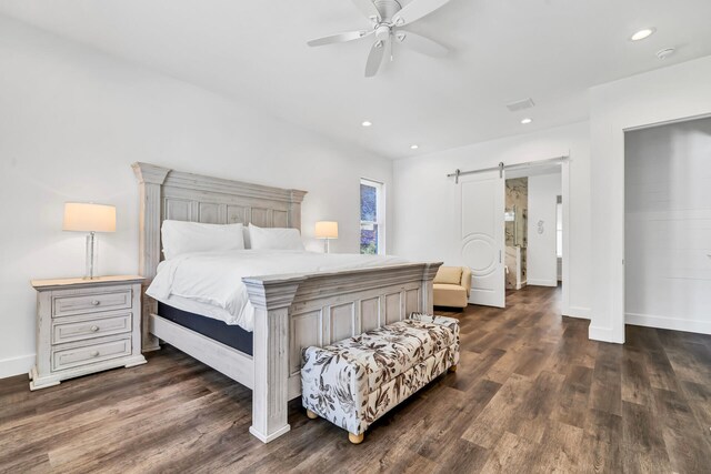 bedroom with dark wood-type flooring, ceiling fan, and a barn door