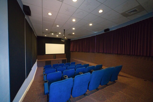 cinema room with a drop ceiling and carpet flooring