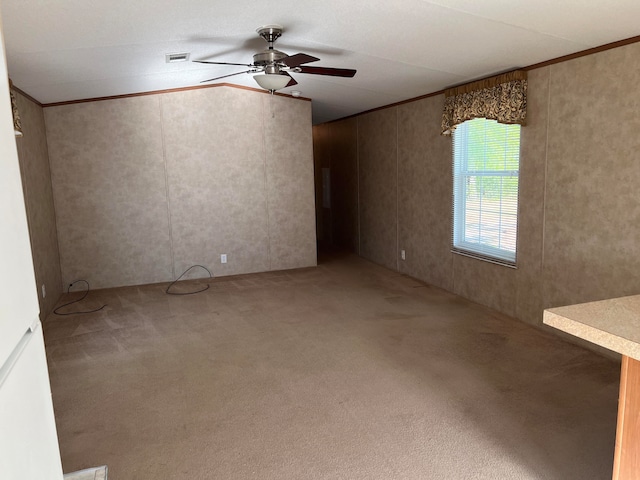 spare room featuring ornamental molding, ceiling fan, and carpet floors