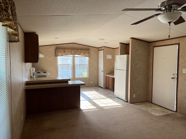 kitchen featuring ceiling fan, a textured ceiling, white refrigerator, light colored carpet, and vaulted ceiling