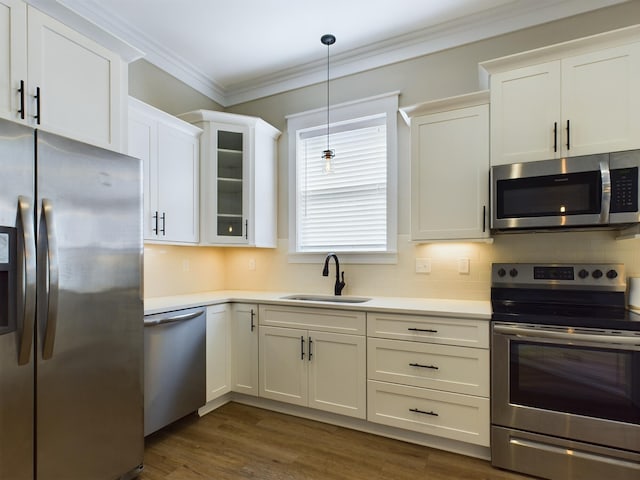 kitchen featuring appliances with stainless steel finishes, crown molding, sink, decorative light fixtures, and dark hardwood / wood-style floors