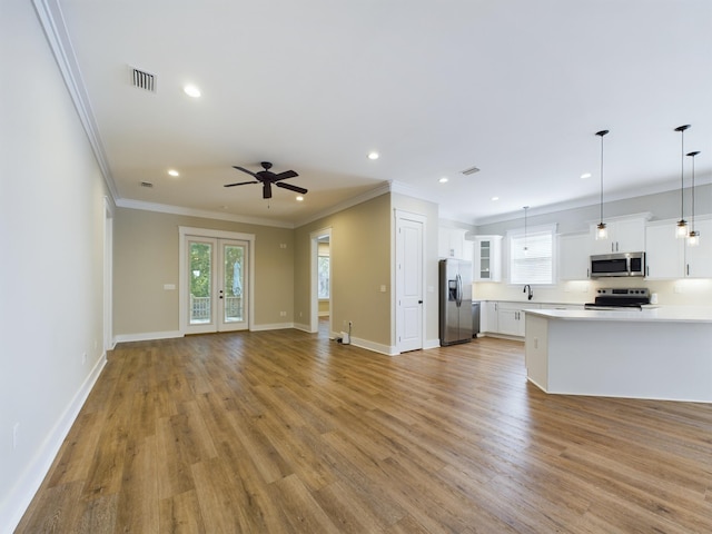 unfurnished living room featuring ceiling fan, light wood-type flooring, and ornamental molding