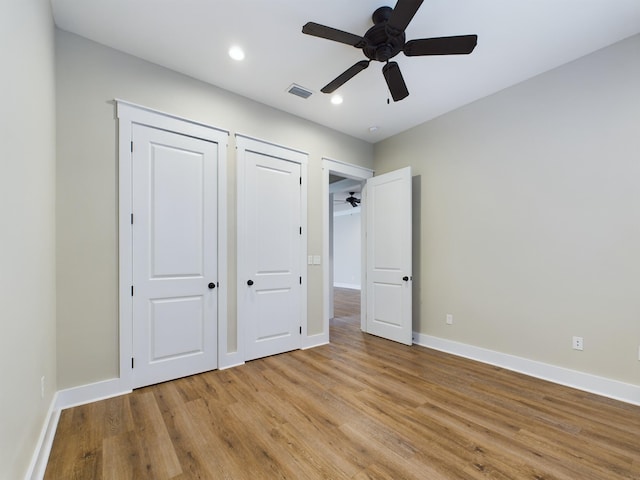 unfurnished bedroom featuring ceiling fan, two closets, and light hardwood / wood-style flooring